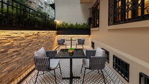 A modern outdoor seating area with a stone wall, a tiled floor, and a glass table surrounded by chairs. - Gleam Collection Hotel (Istanbul)