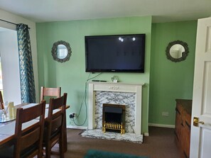 A living room with a fireplace, a television mounted on the wall, and two wall-mounted mirrors.