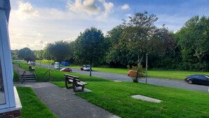 A grassy area with a bench and a sidewalk leading to a road. - Stunning 2-bed Flat in Haverfordwest (Haverfordwest)