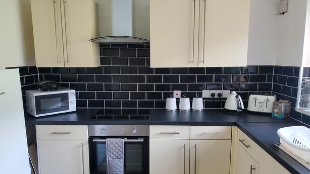 A kitchen with a microwave, toaster, kettle, and oven. - Stunning 2-bed Flat in Haverfordwest (Haverfordwest)
