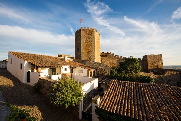 A historic stone tower and surrounding buildings with a cobblestone street.