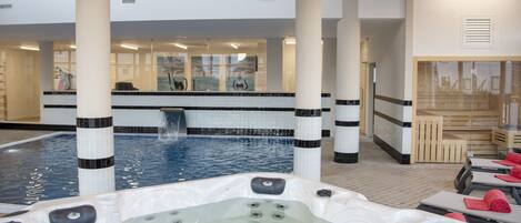 A spa area with a hot tub, a small pool, and a massage table with towels.
