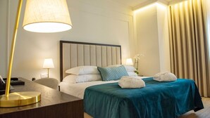 Habitación de hotel con una cama grande, dos lámparas de noche, un escritorio con lámpara y vistas a las cortinas.