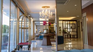Un vestíbulo de hotel con una recepción, una araña y vistas a través de amplios ventanales.