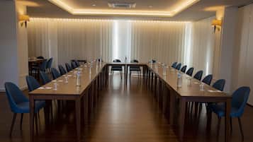Un salón de conferencias con una mesa larga, sillas azules y un diseño de techo moderno.