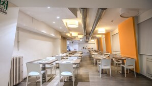 A spacious dining area with multiple tables and chairs, a visible emergency exit sign, and a modern ceiling design with exposed ductwork. - Casa Per Ferie Ravasco San Pietro (Rome)