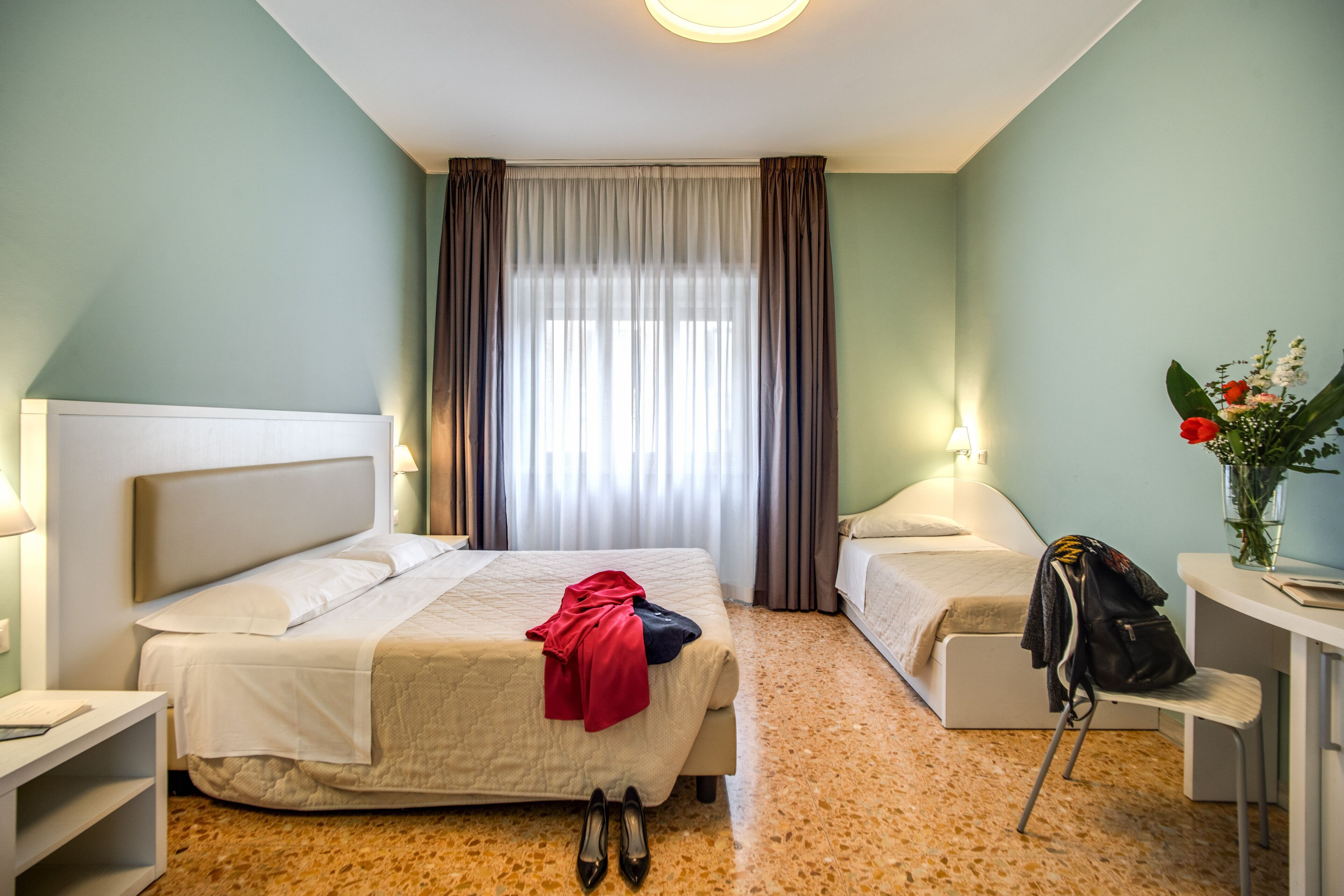 A hotel room with a bed, a desk, a chair, and a nightstand.