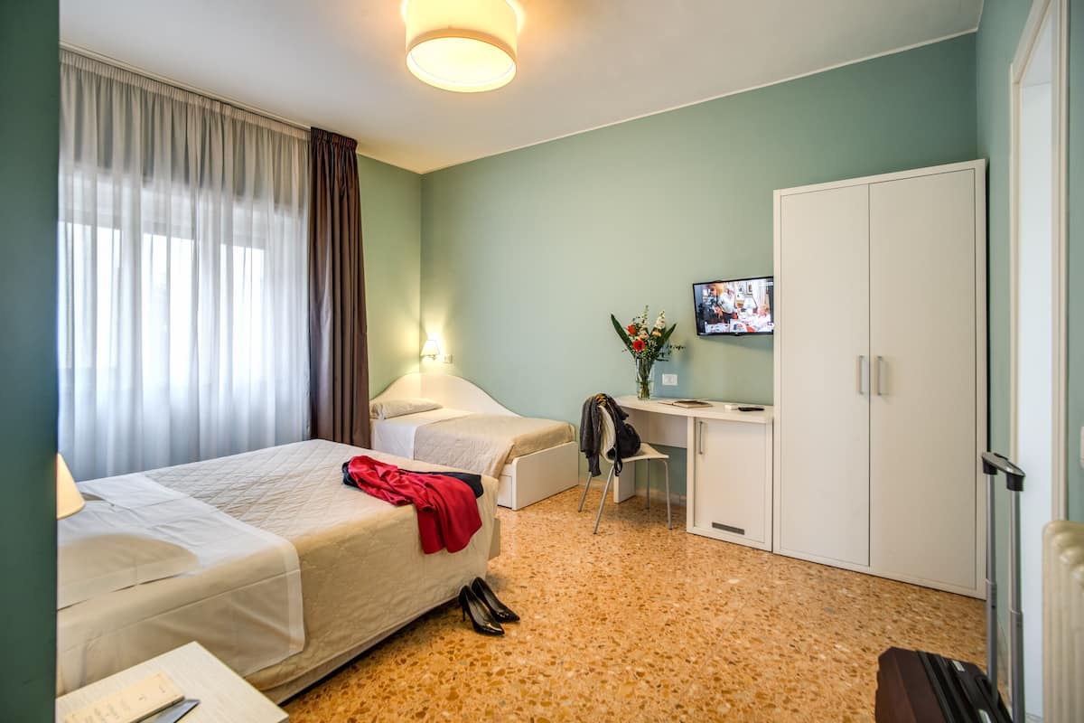 A hotel room with two beds, a desk, a TV, and a wardrobe.