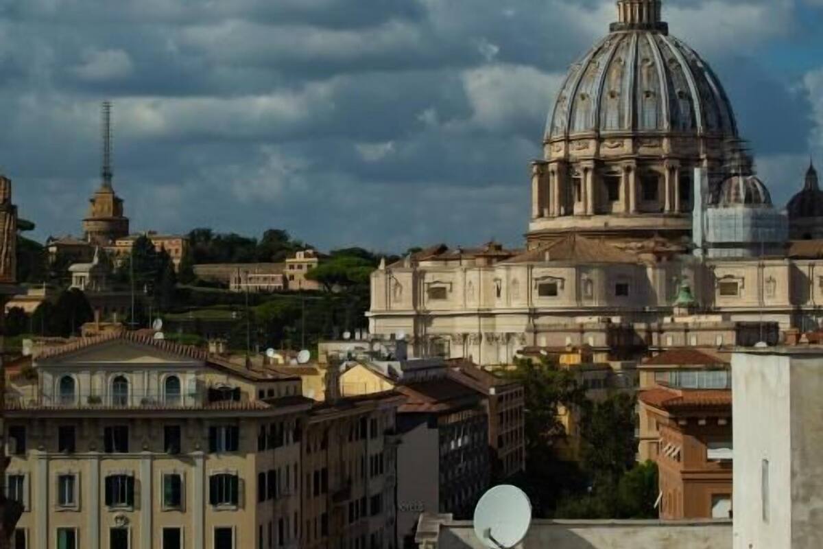 A view of a cityscape with a prominent dome structure, likely a historical or religious building, surrounded by other buildings and a partly cloudy sky.
