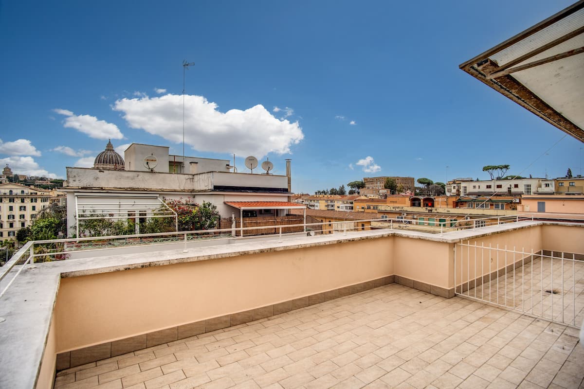 A rooftop terrace with a view of surrounding buildings, including a dome structure and a church.