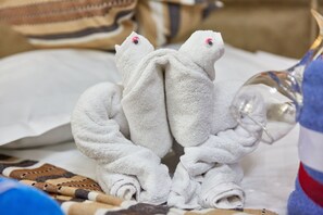 A towel arranged in the shape of a frog, with a bottle and a striped pillow in the background. - Apartamente Papaya (Navodari)