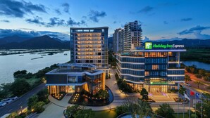 Un hôtel Holiday Inn Express au design moderne, entouré d’eau et de montagnes.