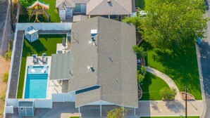 Vue aérienne d’une propriété résidentielle dotée d’une piscine, d’un patio couvert et d’une pelouse bien entretenue.