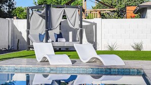 Un espace piscine comprenant deux chaises longues et un coin salon abrité.