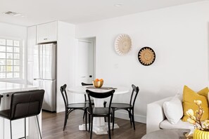 A modern kitchen with white cabinetry, a dining area with a round table and chairs, and a living room with a sofa and cushions. - 8 Min to Old Town | 2 Master Suites | Heated Pool | Best Location | Sleeps 10 (Phoenix)