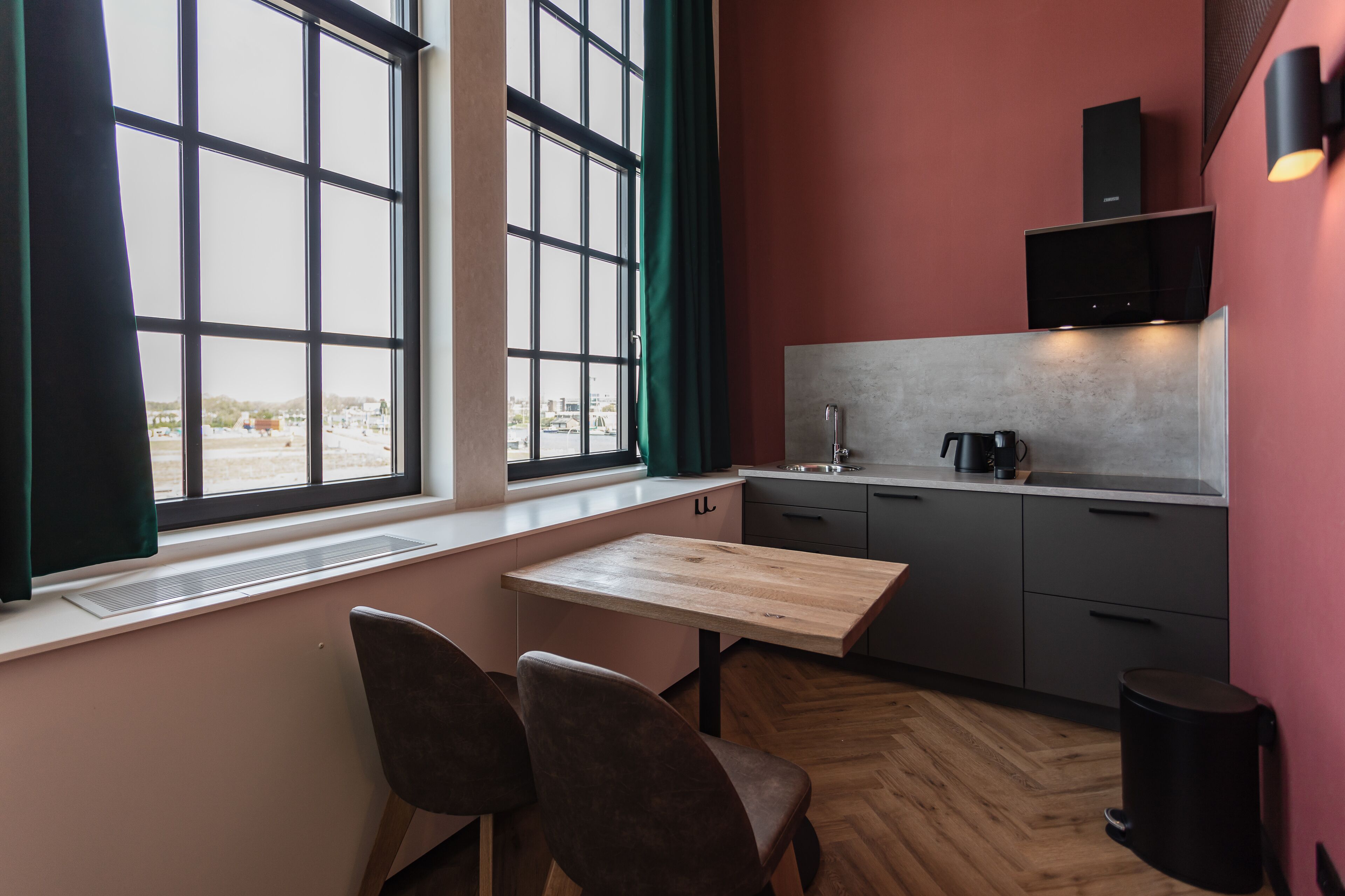 Una cocina compacta con ventana, una mesa pequeña, dos sillas y un microondas.
