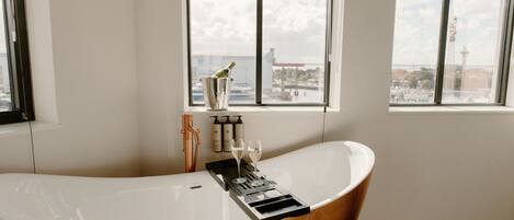 A modern bathroom with a freestanding bathtub, a window with a view of the city, and a towel rack.