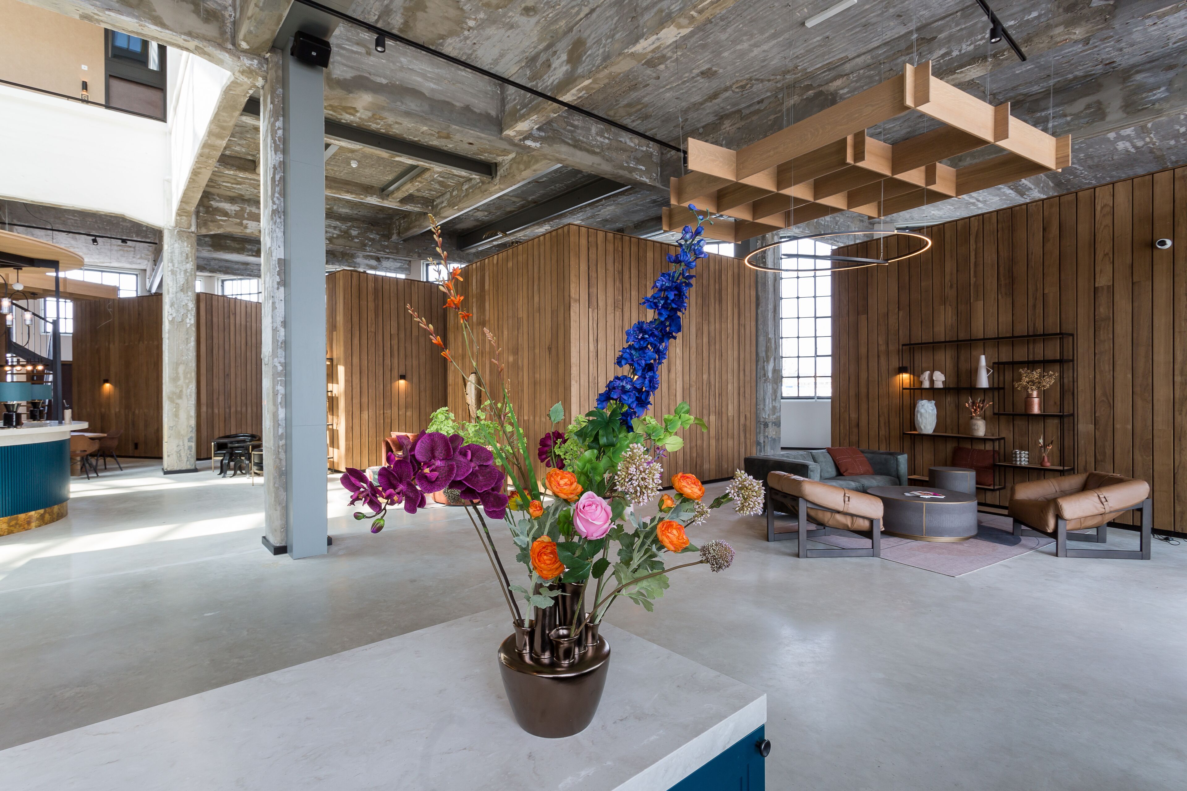A modern interior with a central floral arrangement, wooden panel walls, and a seating area with a round coffee table.