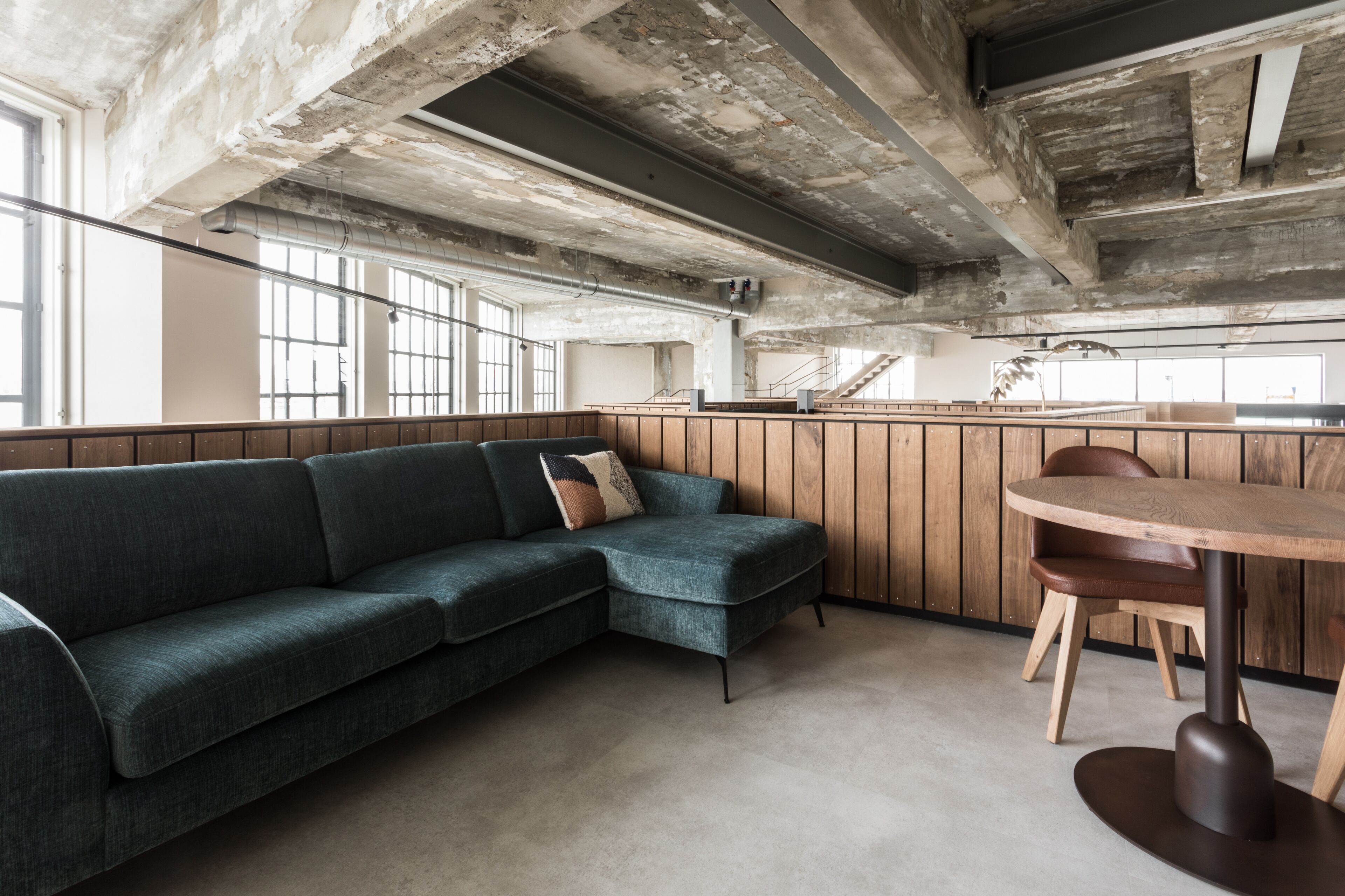 A modern interior with a sectional sofa, a round wooden table, and a staircase leading to an upper level.