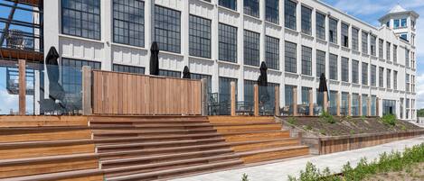 A modern building with large windows and a wooden staircase leading to a terrace.