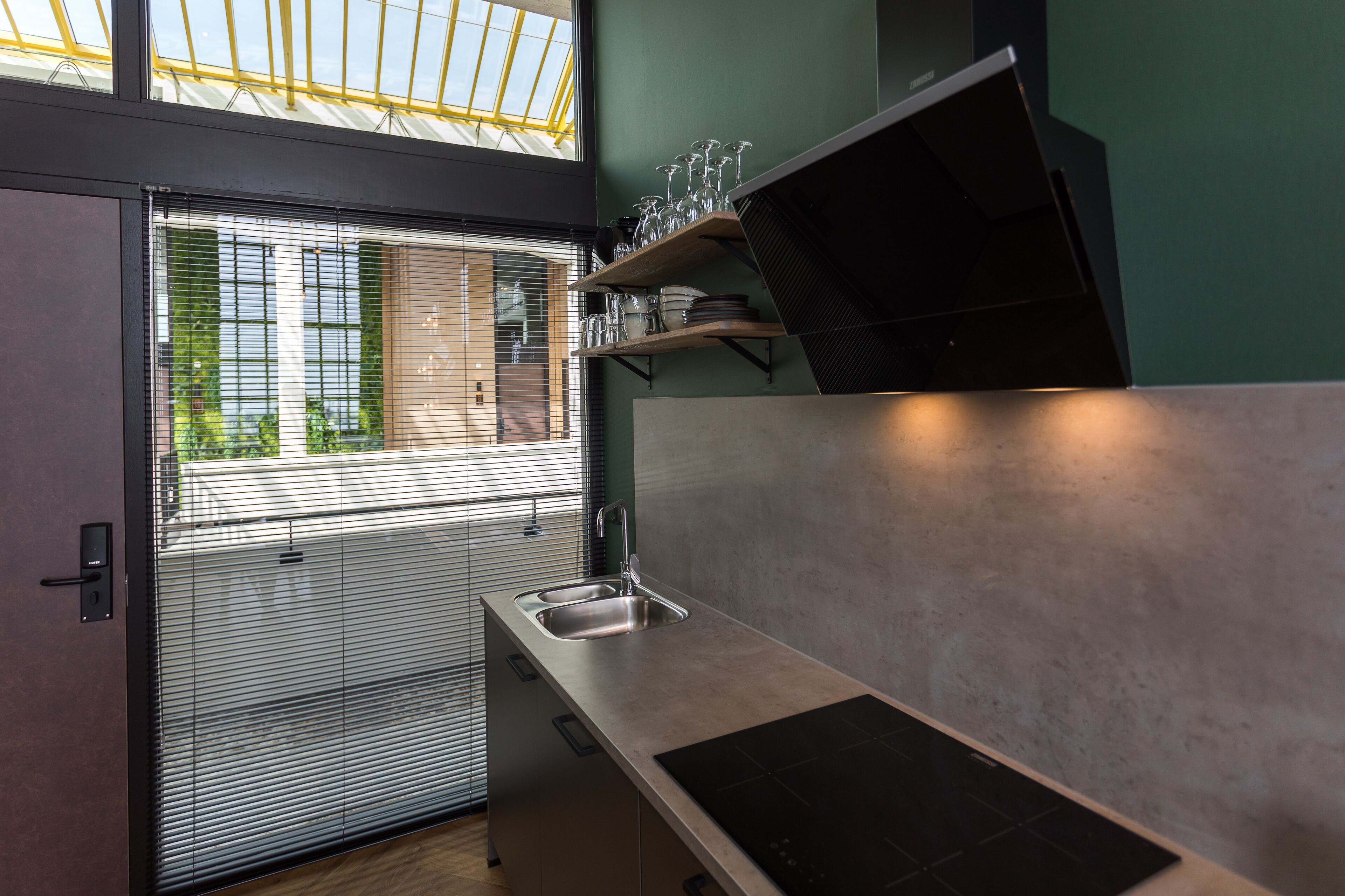 A modern kitchen with a built-in sink, a black countertop, and a skylight above.