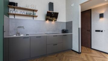 A modern kitchen with grey cabinets, a stainless steel sink, and wooden shelves above.
