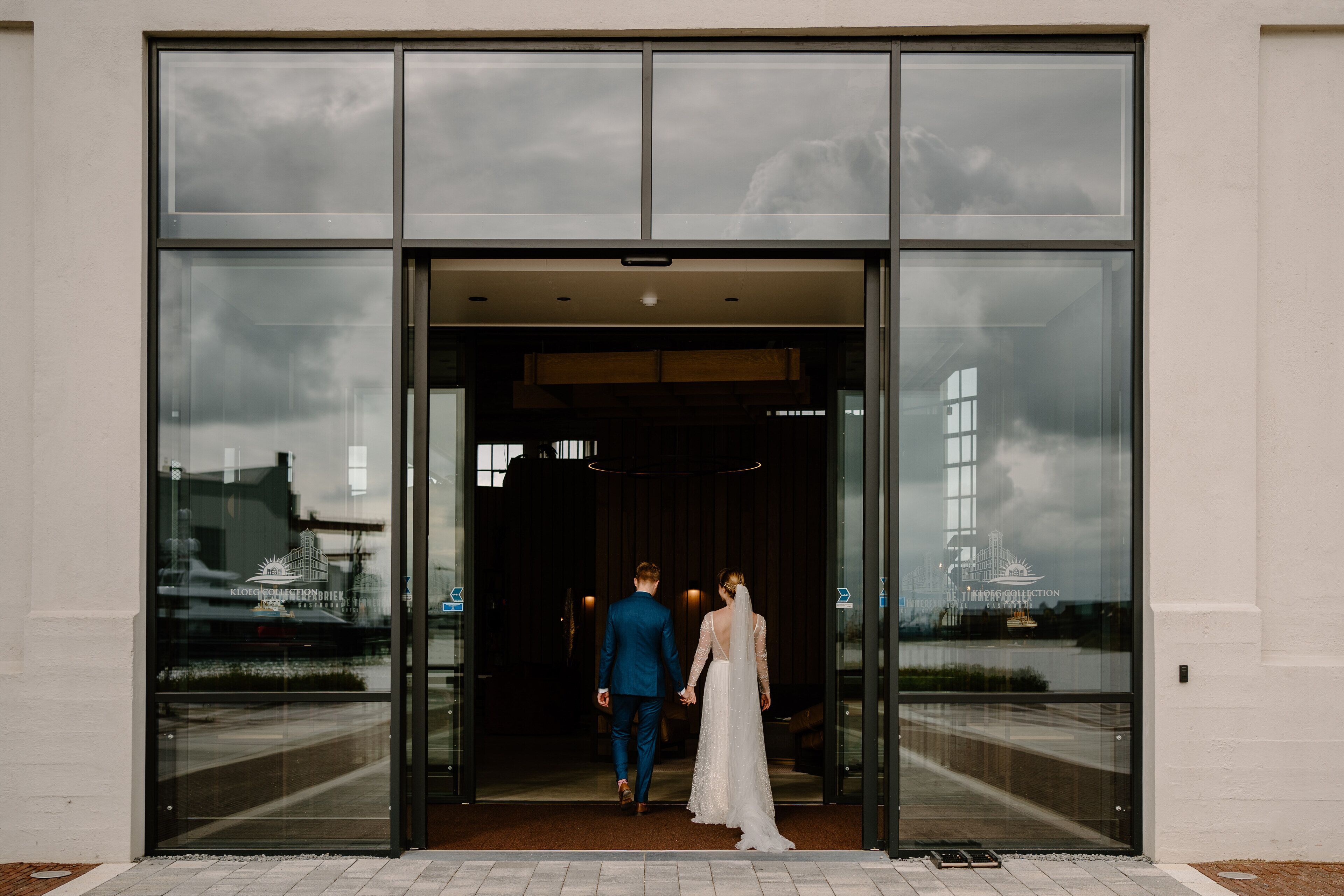A couple exiting a building with large glass doors.