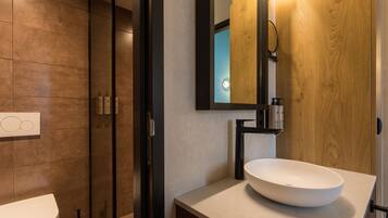 Un baño moderno con un espejo grande, un lavabo blanco y una zona de ducha.