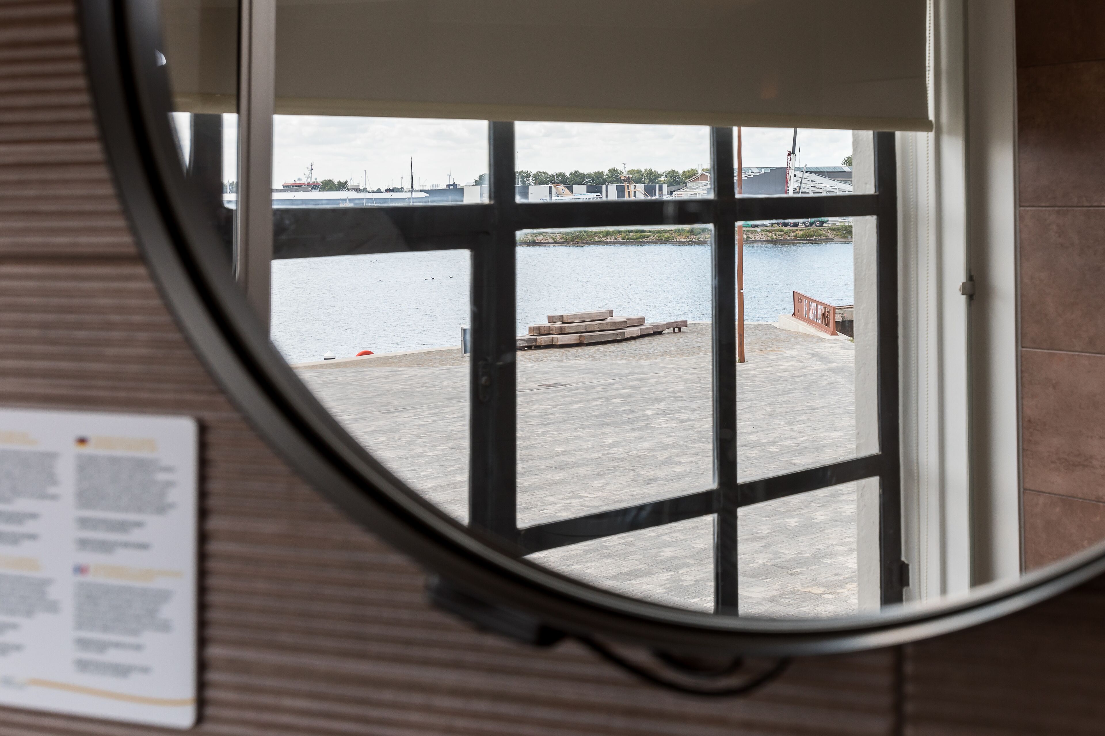 A view through a window with a view of a waterfront area, including a dock and a building in the background.