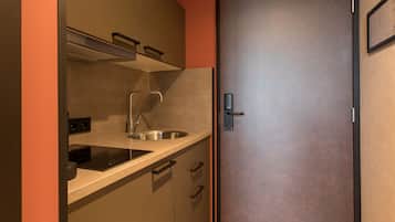 A compact kitchen with a stainless steel sink, a built-in oven, and a door with a handle.