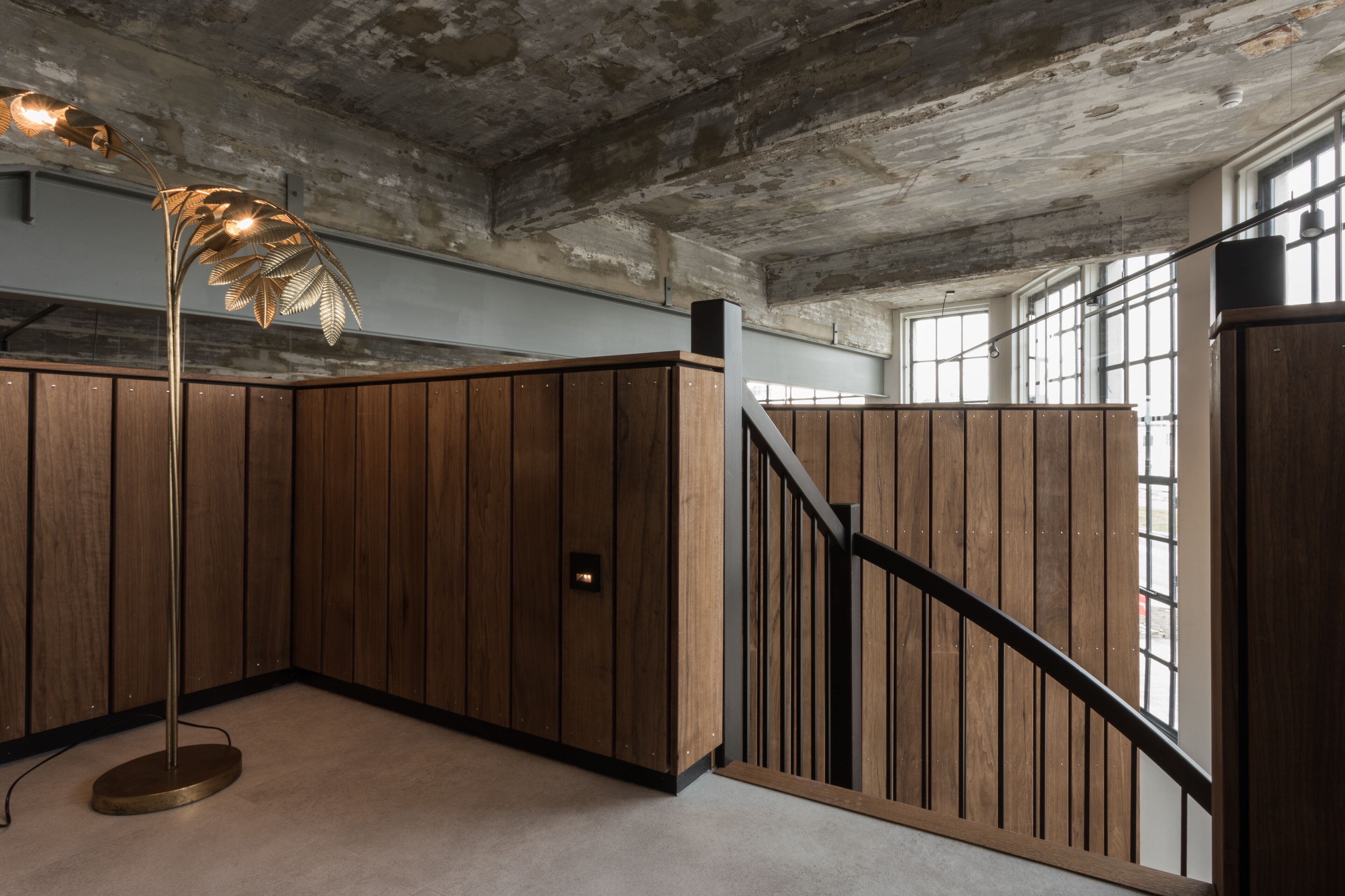 A modern interior with a wooden panel wall, a spiral staircase, and a floor lamp.