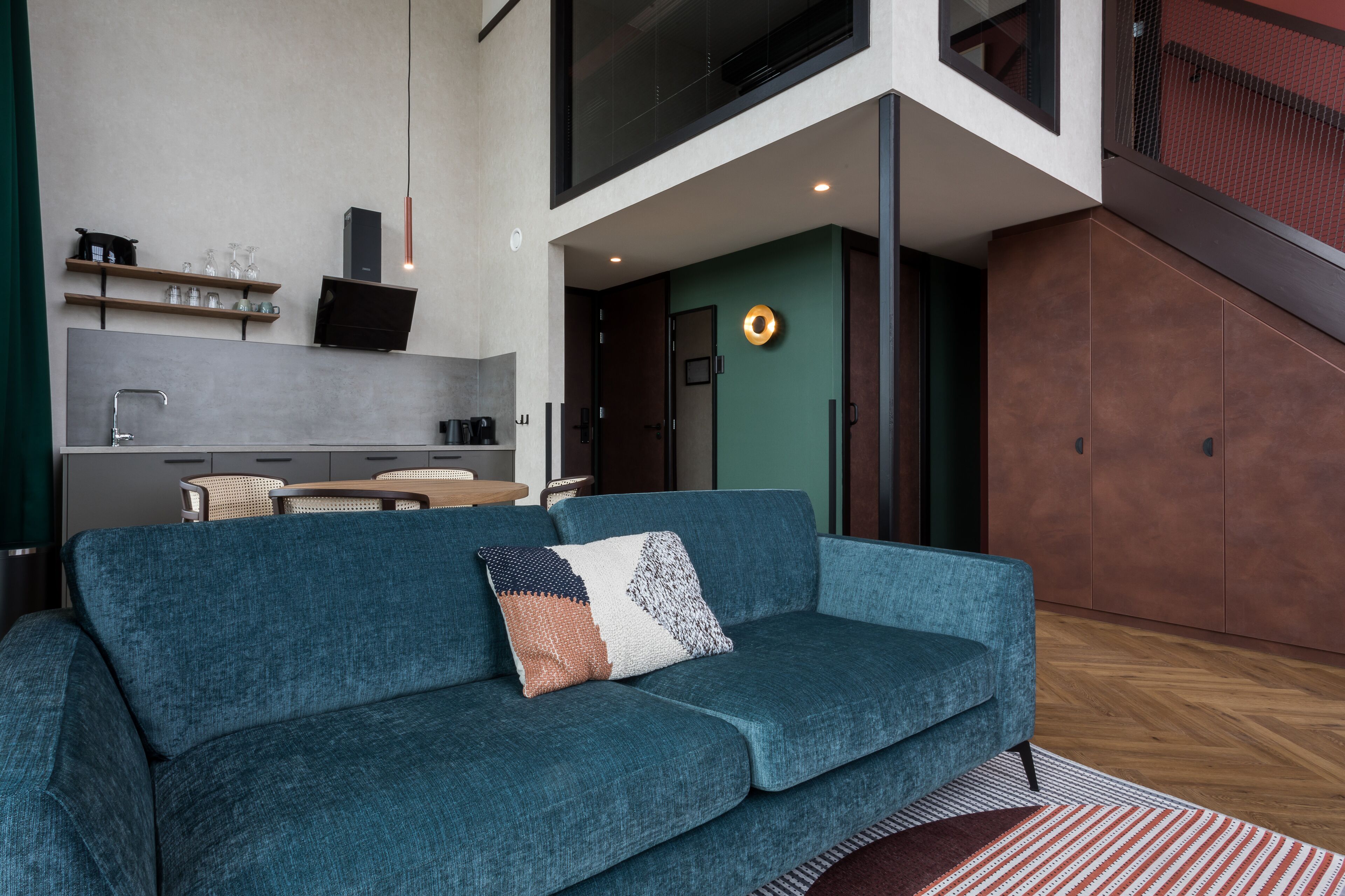 En moderne stue med en turkis sofa, et sofabord og et køkkenområde med et spisebord og stole.