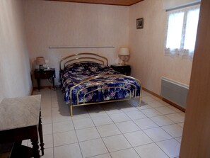 Um quarto com uma cama, duas mesas de cabeceira, um criado-mudo, uma janela e uma porta.