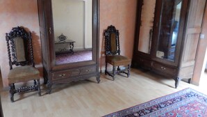 Een kamer met twee sierlijke houten meubelstukken, een spiegel en een kamerkleed met een patroon.
