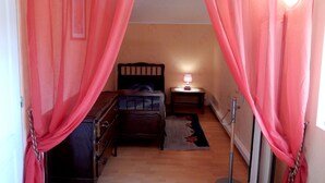 Een slaapkamer met een bed, nachtkastje, lamp en gordijnen.