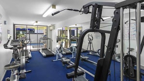 A gym with exercise equipment, treadmills, and a blue carpeted floor. - Open 1 Bedroom Apartment in Brisbane City (Brisbane)