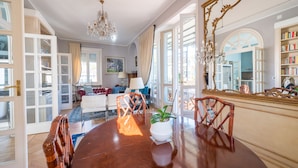 A dining area with a wooden table, chairs, and a chandelier. There is a large mirror on the wall and a bookshelf filled with books. - Lovely apartment with furnished terrace (Torino)
