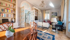 A spacious living room with a wooden dining table, chairs, a sofa, and a bookshelf filled with books. - Lovely apartment with furnished terrace (Torino)