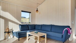 Una sala de estar moderna con un sofá seccional azul, una mesa de centro de madera y un ventanal con vistas al exterior.