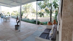 Un patio exterior con una zona de estar techada, una mesa de comedor y sillas.