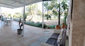 An outdoor patio with a covered seating area, a dining table, and chairs. - La Casetta Apartment (Manduria)