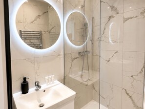 A bathroom with a sink, mirror, and shower.