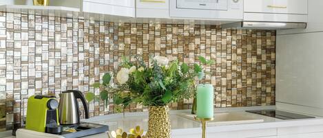 A modern kitchen with white cabinets, a tiled backsplash, and a central island with chairs.
