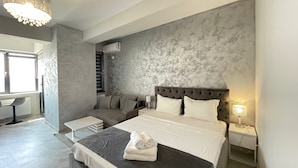 Un dormitorio moderno con una cama grande, cabecera capitonada y pared gris con textura.