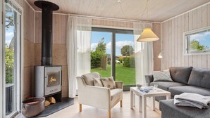 A cozy living room with a fireplace, comfortable seating, and a view of the garden. - 2 bedroom stunning home in Otterup (Otterup)