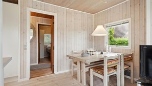 A cozy room with a wooden interior, a dining table with chairs, a TV, and a window with a view of greenery. - 2 bedroom stunning home in Otterup (Otterup)