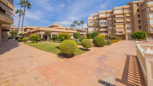 A courtyard with tiled flooring, palm trees, and a building with multiple balconies. - Cubo's Apartment Costa del Oro / close to beach / free wifi (Torrox Costa)