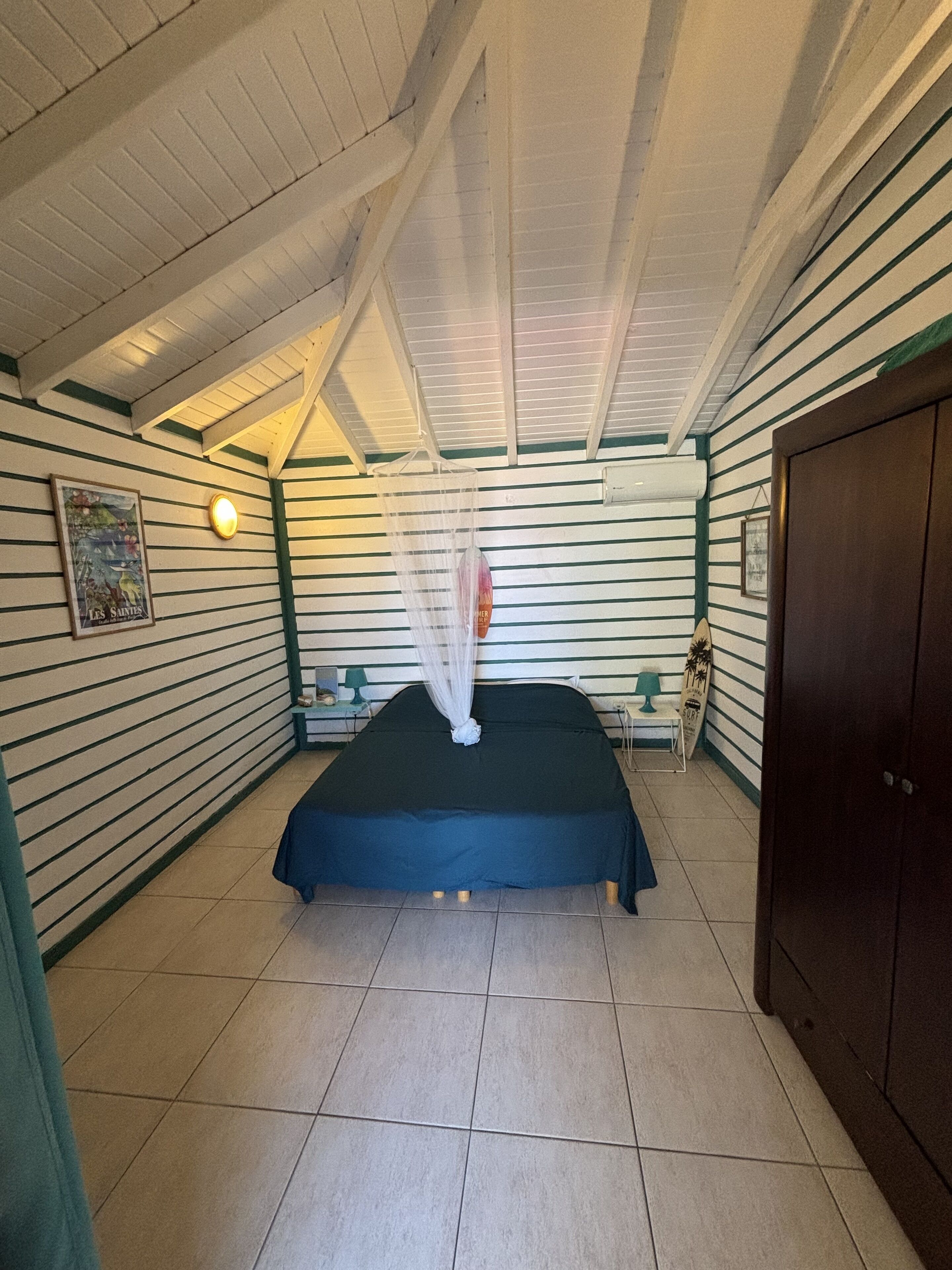 A room with a bed, a nightstand, a wall-mounted air conditioner, and a door.