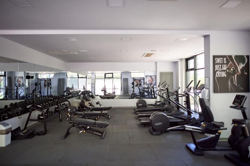 A gym with various exercise equipment, large windows, and motivational posters.