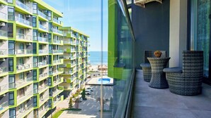 A high-rise building with multiple balconies, a pool, and a view of the sea.